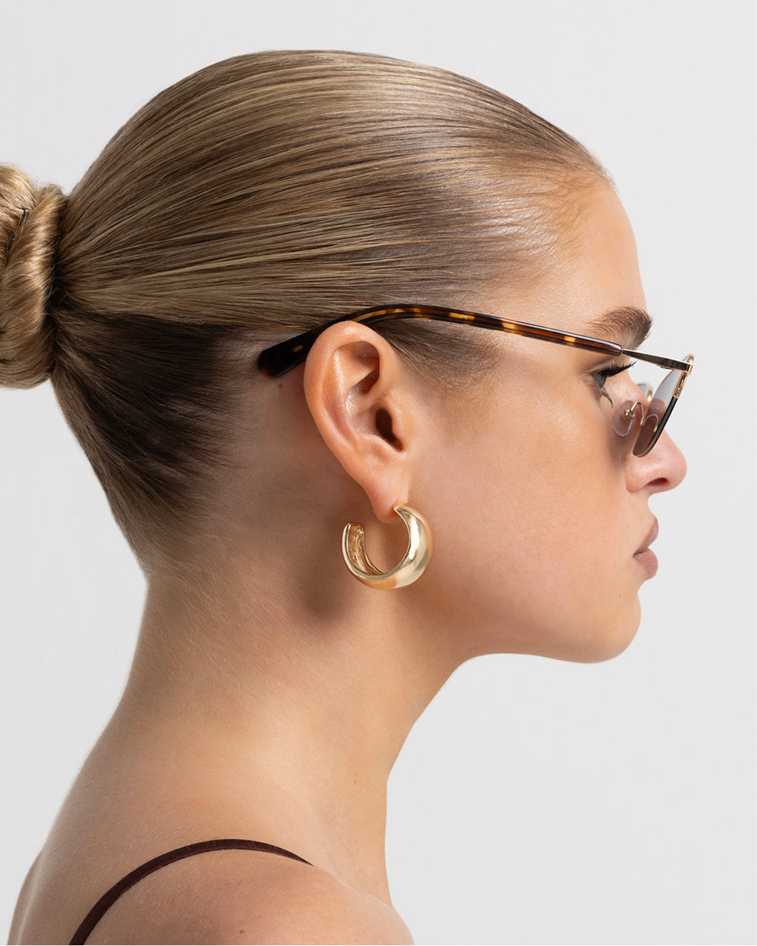 Women’s gold-tone metal and tortoiseshell accents, cat-eye sunglasses with rectangular tinted lenses, thin frame, side view on model