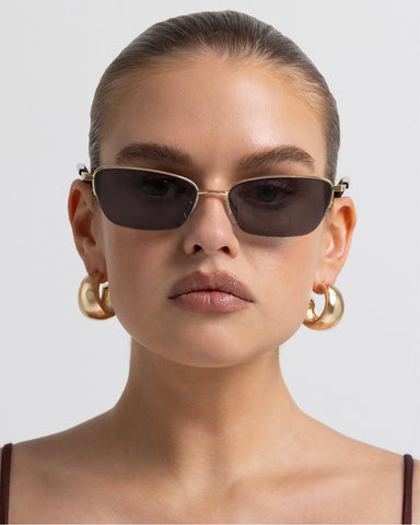 Women’s gold-tone metal and tortoiseshell accents, cat-eye sunglasses with rectangular tinted lenses, thin frame, front view on model
