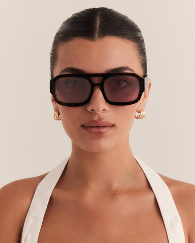 Female wearing modern aviator sunglasses with square acetate tortoiseshell frame and polarised lenses featuring gold embossed logo detail front view.