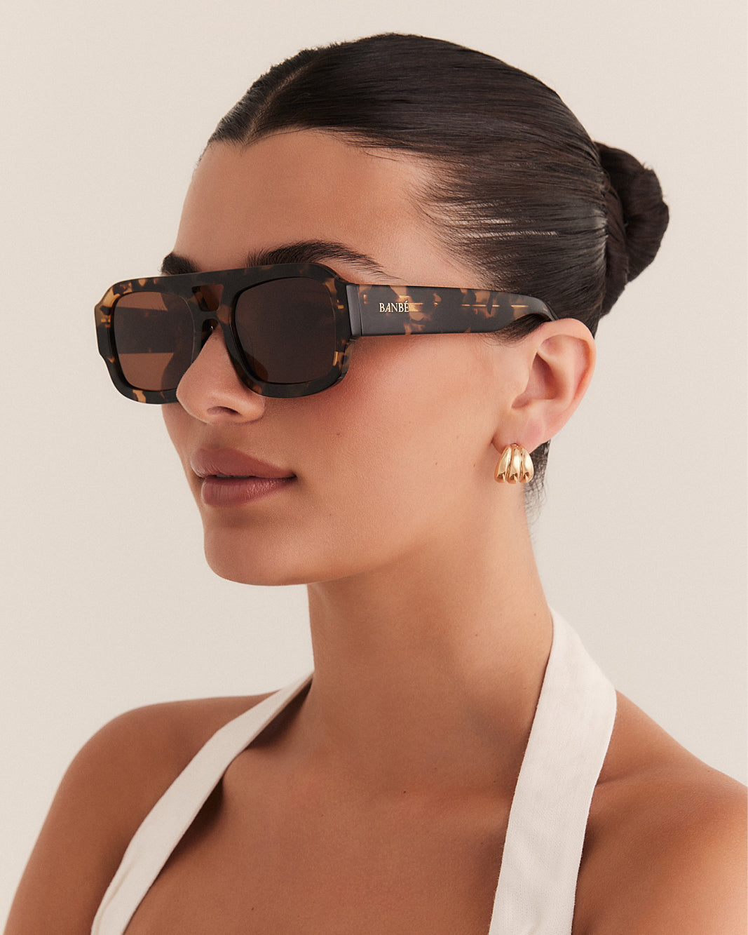 Female wearing modern aviator sunglasses with square acetate tortoiseshell frame and polarised lenses featuring gold embossed logo detail side view.