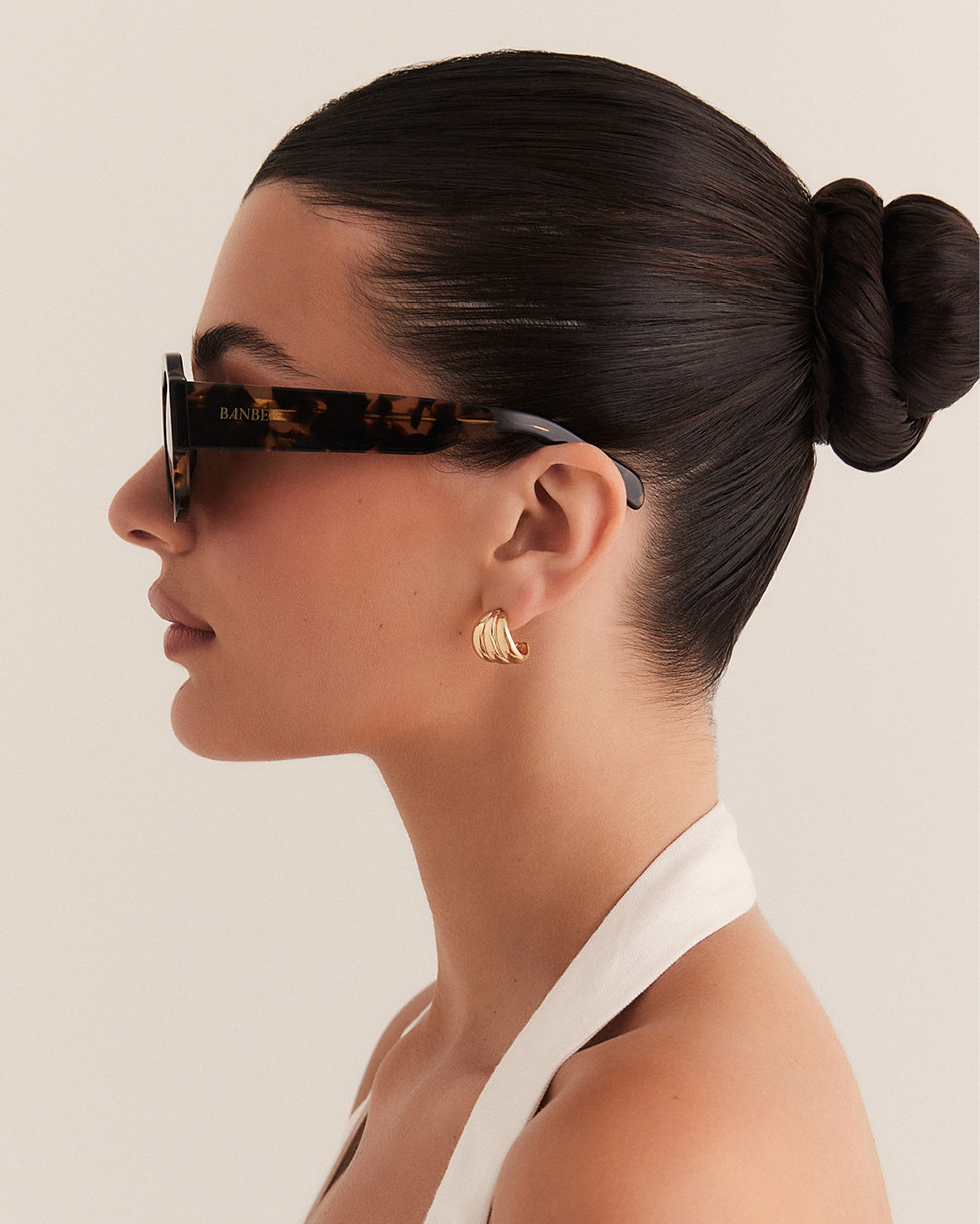 Female wearing modern aviator sunglasses with square acetate tortoiseshell frame and polarised lenses featuring gold embossed logo detail side view.
