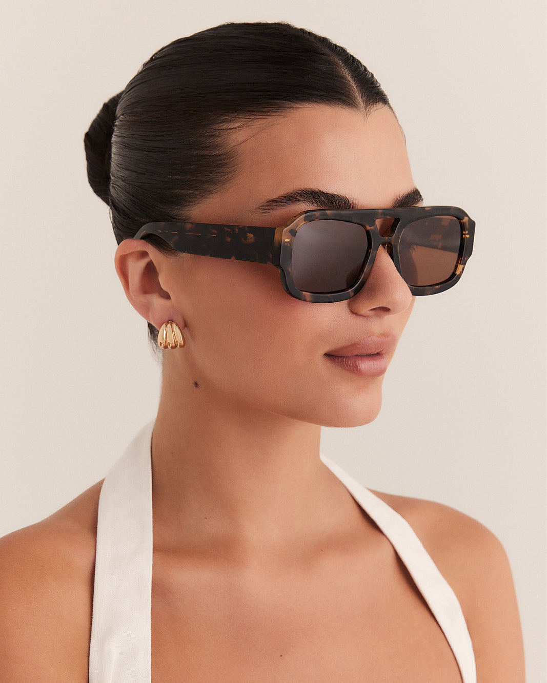 Female wearing modern aviator sunglasses with square acetate tortoiseshell frame and polarised lenses featuring gold embossed logo detail side view.