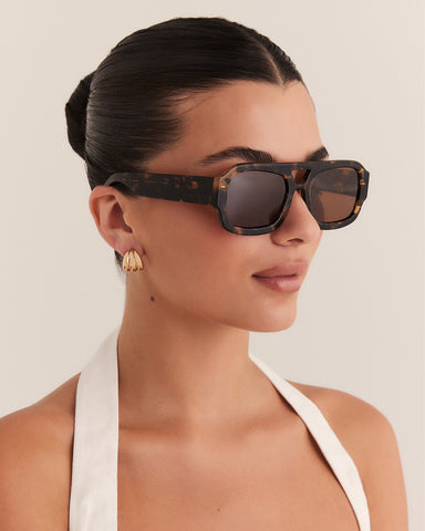 Female wearing modern aviator sunglasses with square acetate tortoiseshell frame and polarised lenses featuring gold embossed logo detail side view.