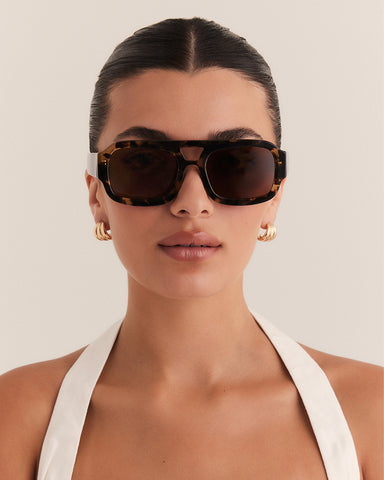 Female wearing modern aviator sunglasses with square acetate tortoiseshell frame and polarised lenses featuring gold embossed logo detail front view.